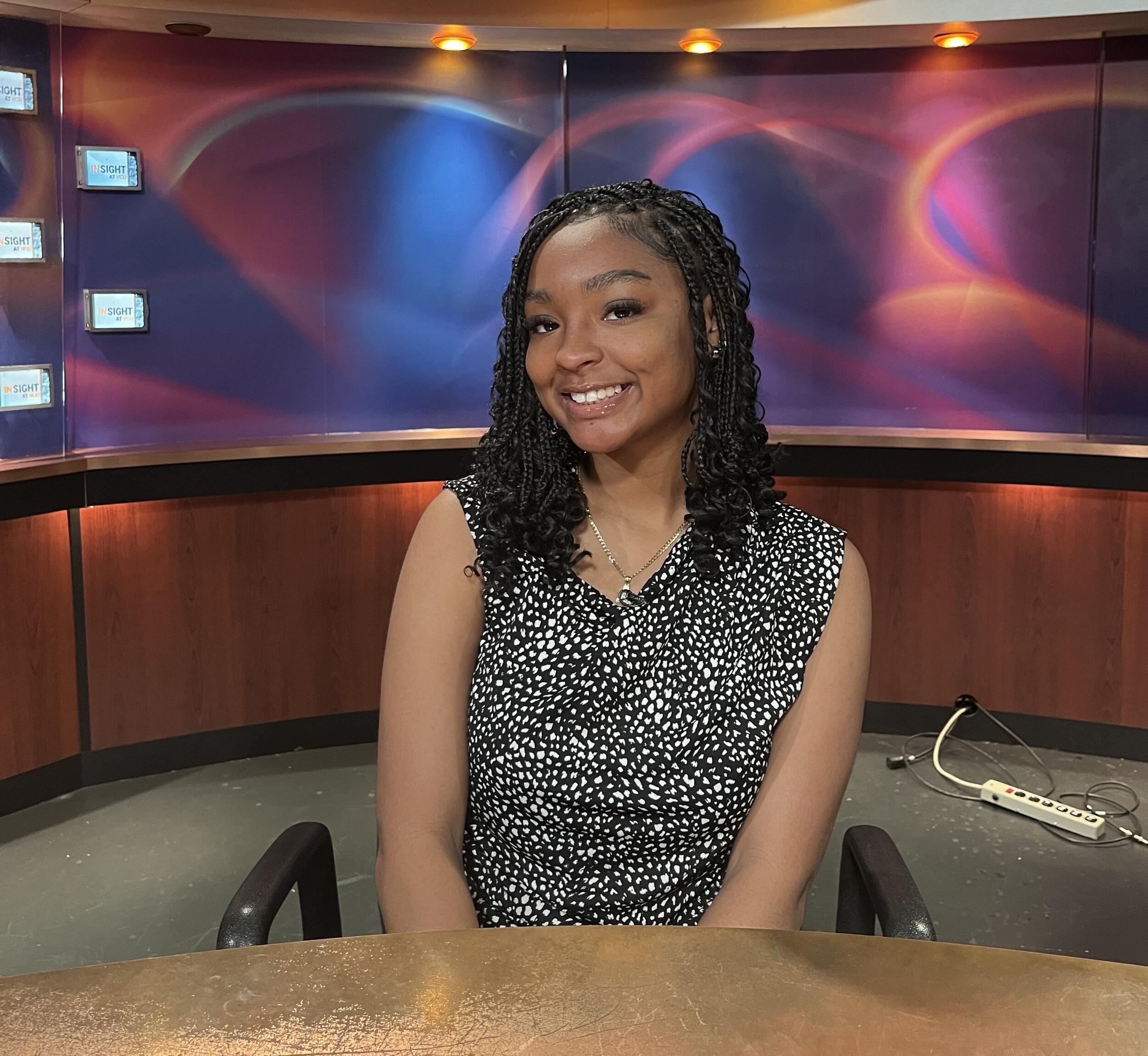 A photo of a woman sitting at a news desk. 