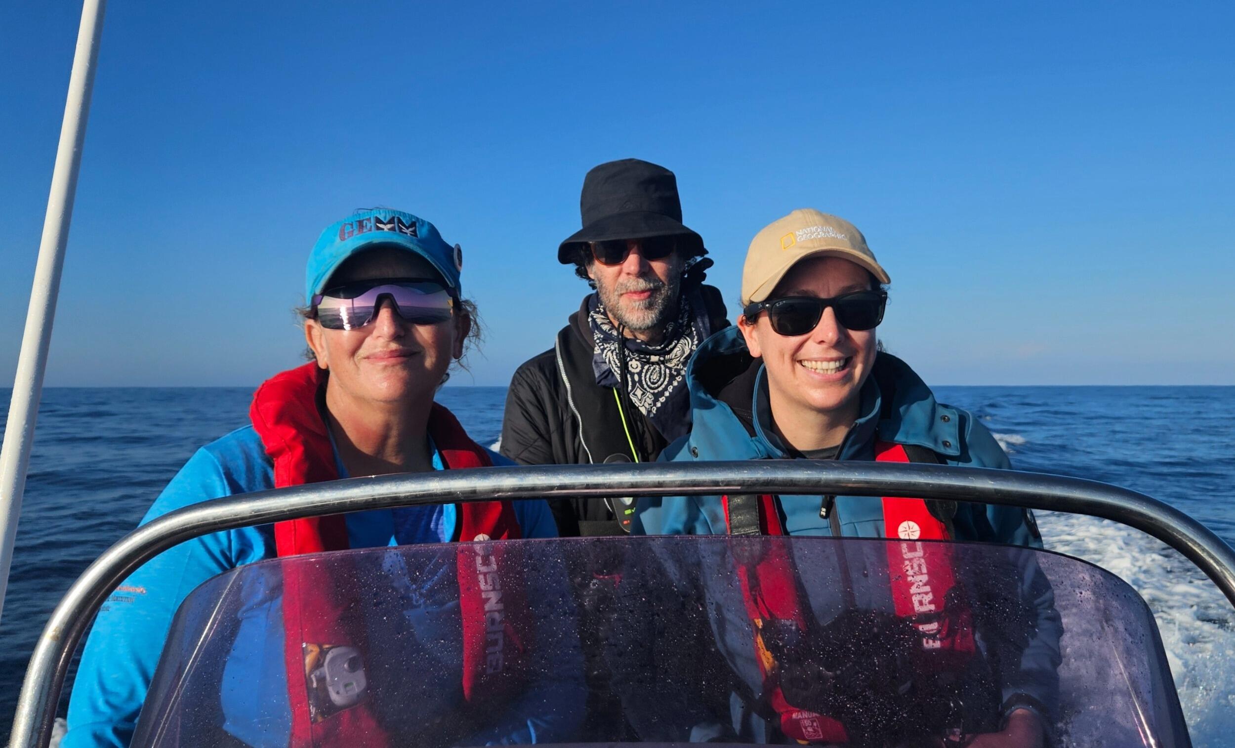 A photo of three people standing on a boat. 