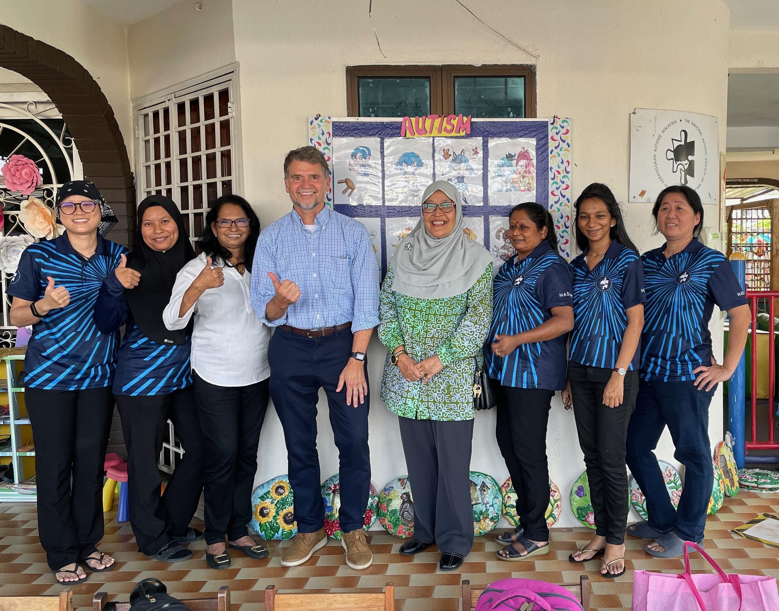 Eight people standing next to eachother in a group photo. 