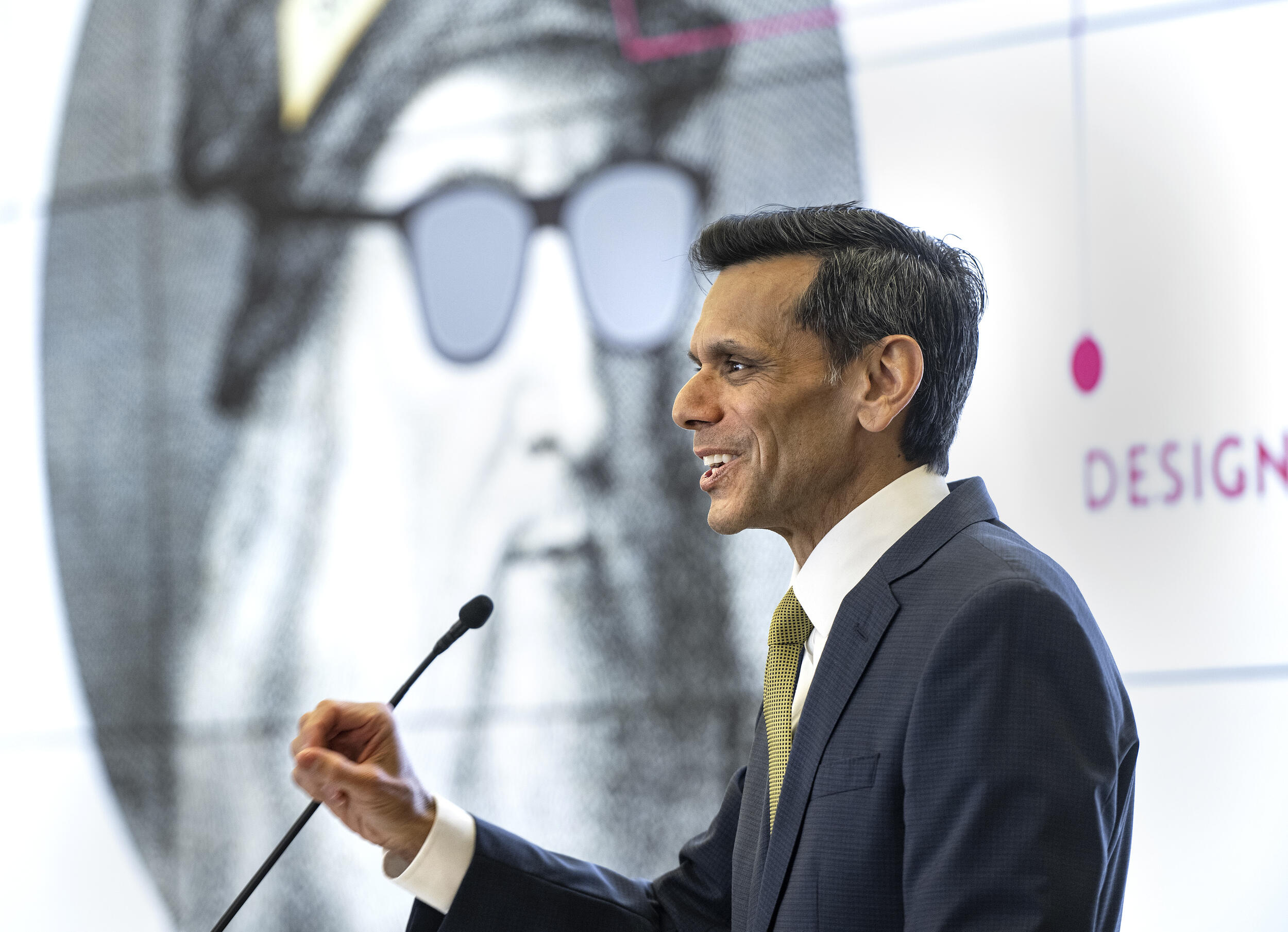 A photo of a man speaking into a microphone. 