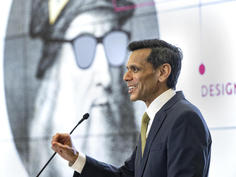 A photo of a man speaking into a microphone. 