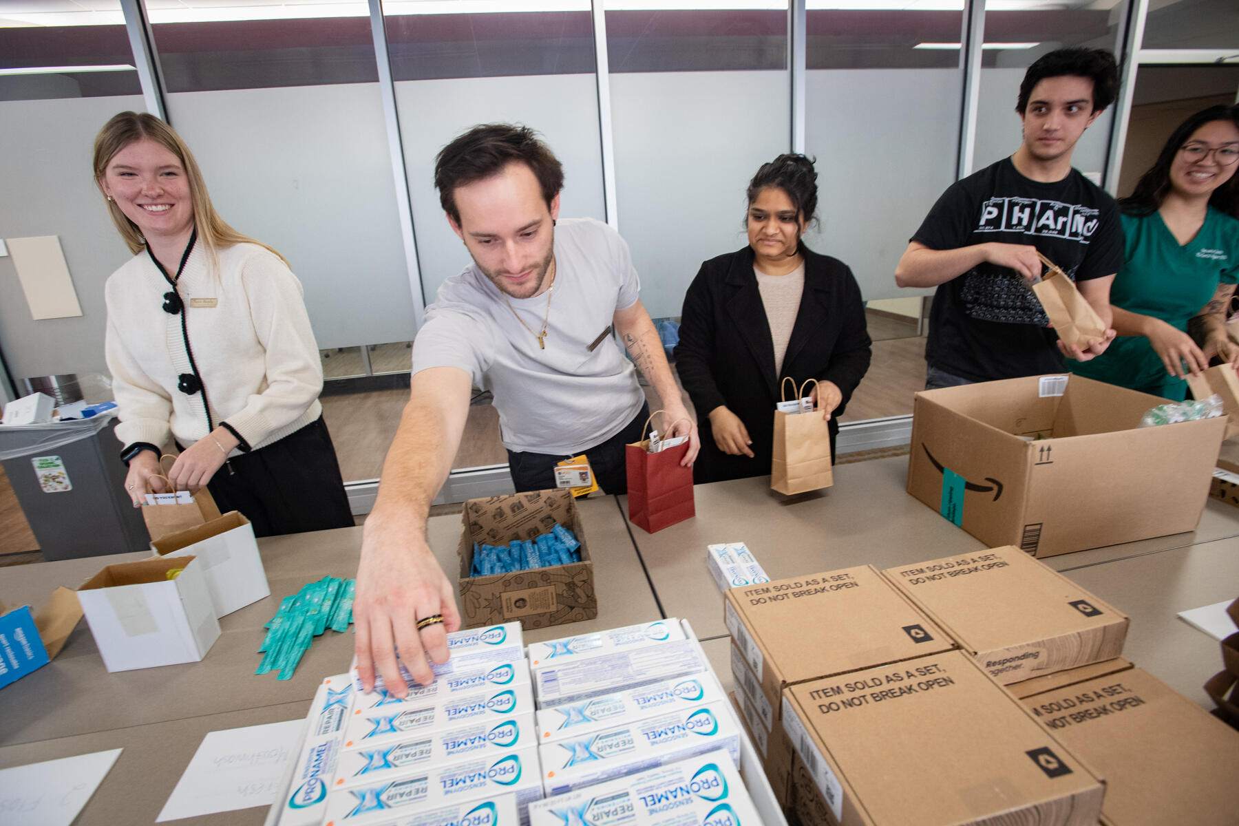 A photo of four people packing bags with dental care items. 