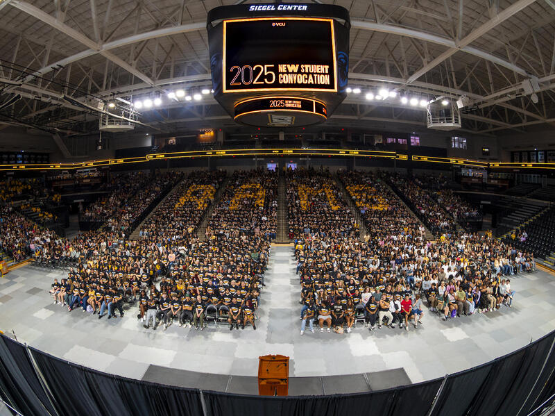  A photo of a crowd of people sitting in a basketball arena. 