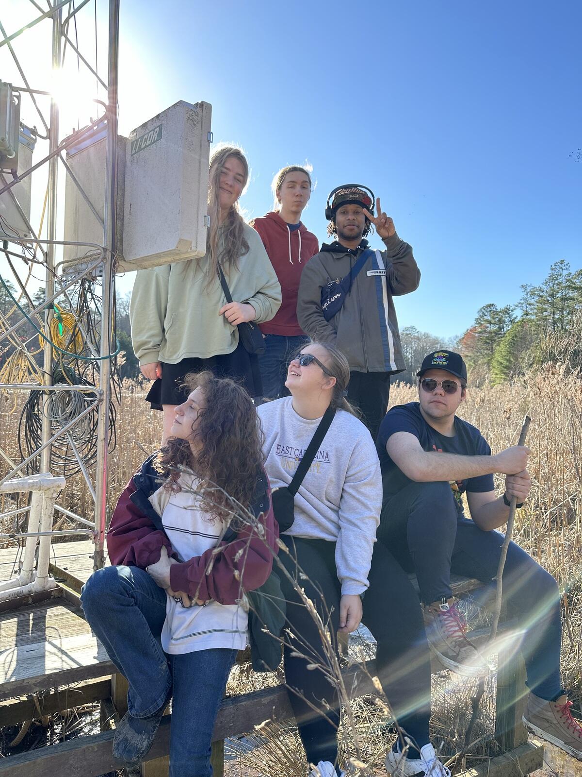 A photo of six people next to a data collection tower. 