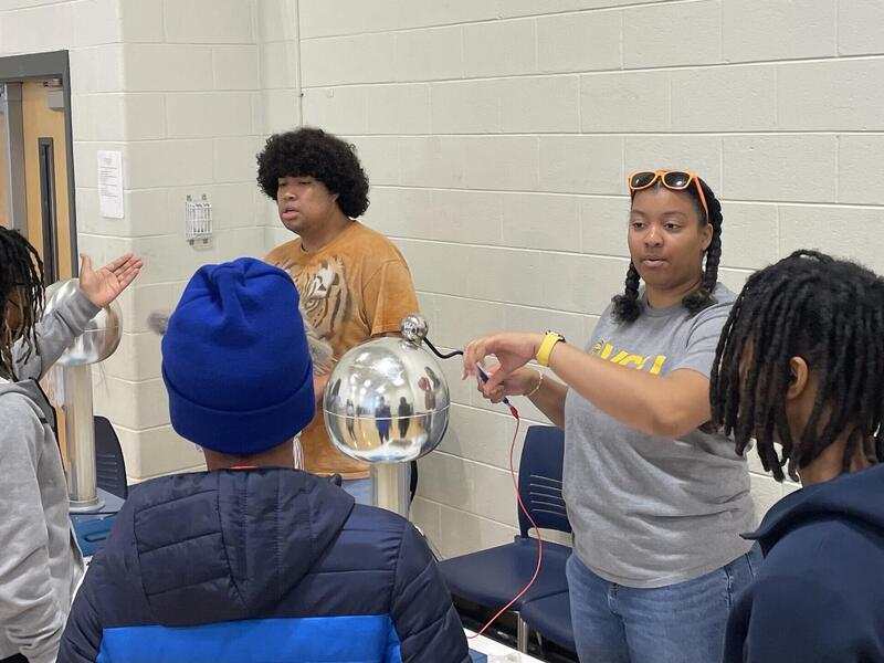A photo of two adults standing in front of three children. 