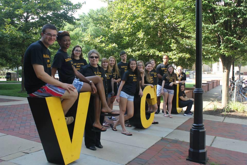 A group of students and a faculty member pose for a photo arranged around the letters V-C-U.