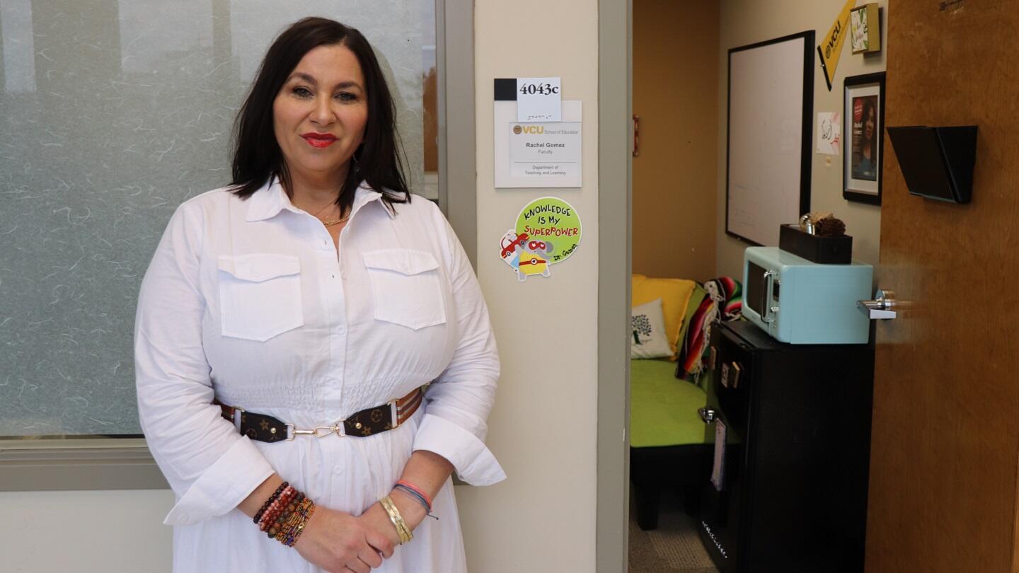 A woman standing in front of a window next to an open door. 