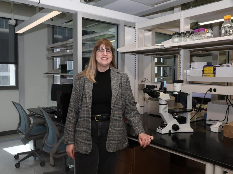 A photo of a woman standing next to a counter. 