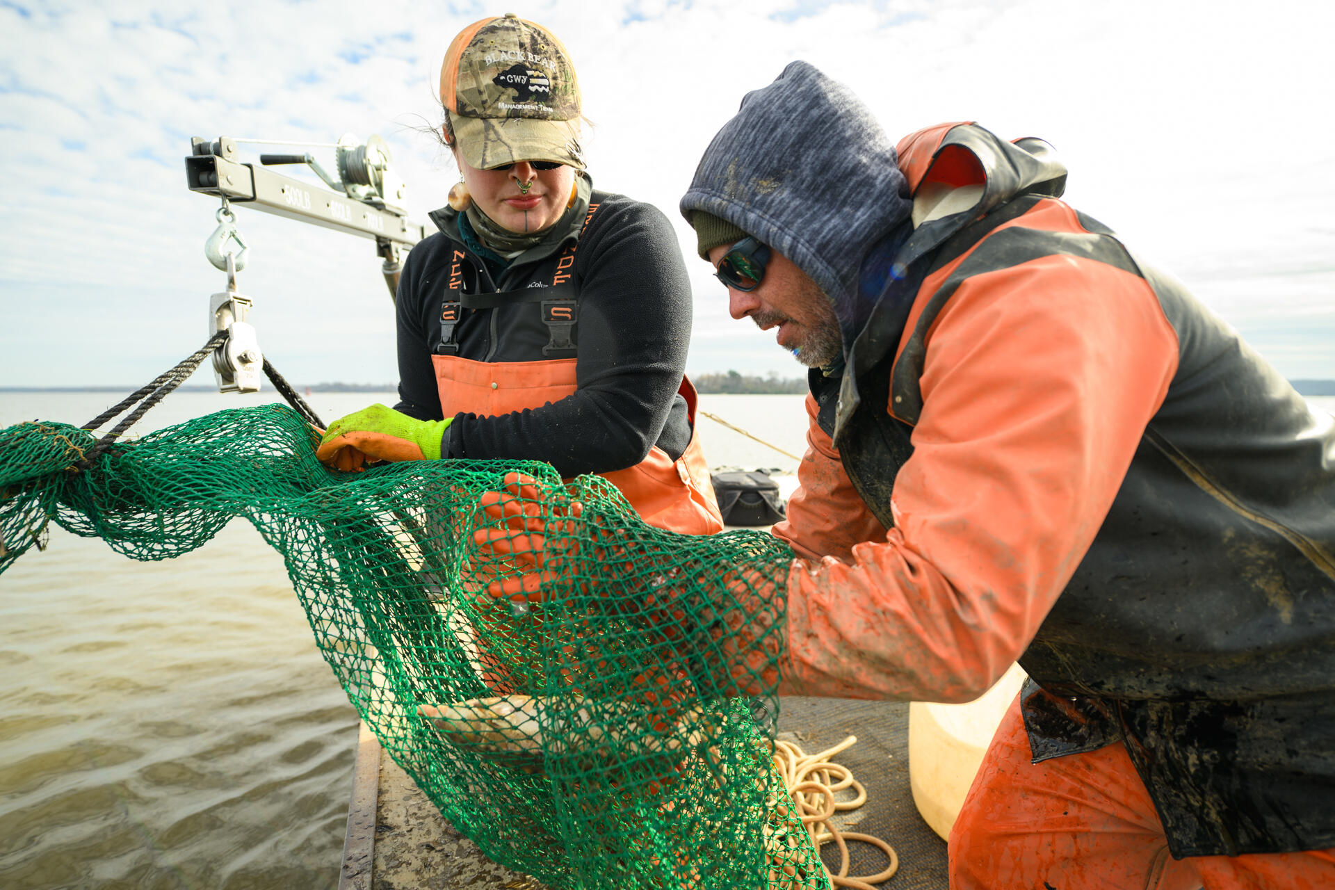 A photo of two people holding a green fishing net with a fish inside of it.