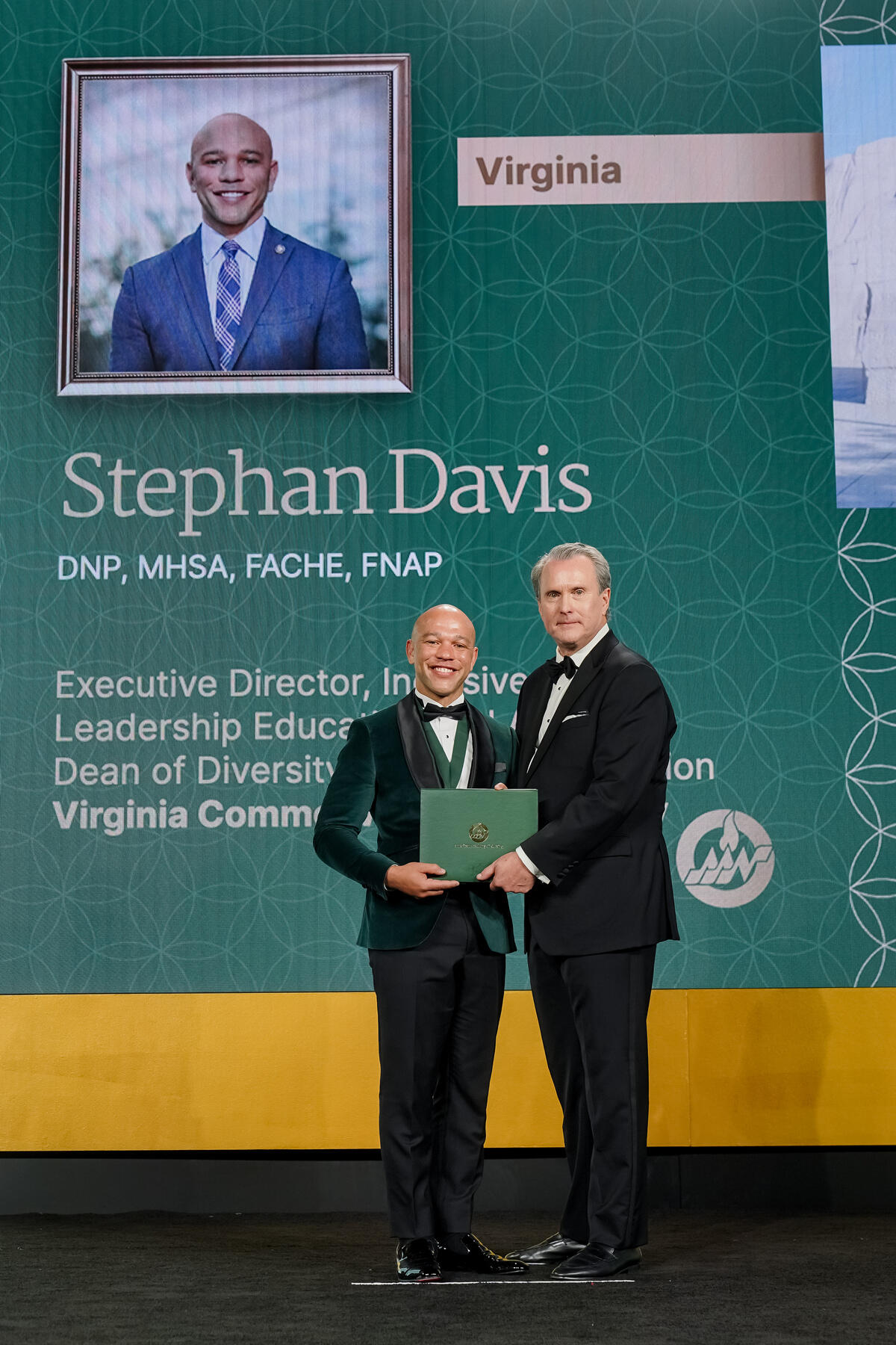 Stephan Davis stands on a stage, posing with Ken White.