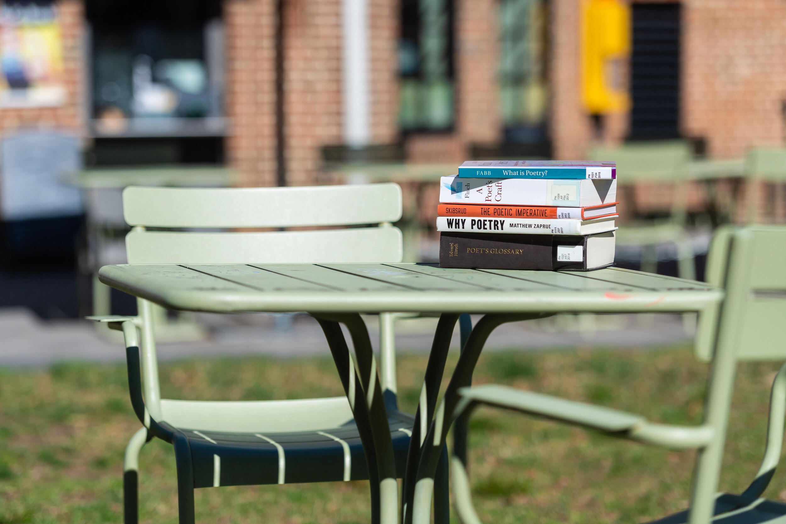 Table with stack of books with titles like Why Poetry and The Poetry Imperative.
