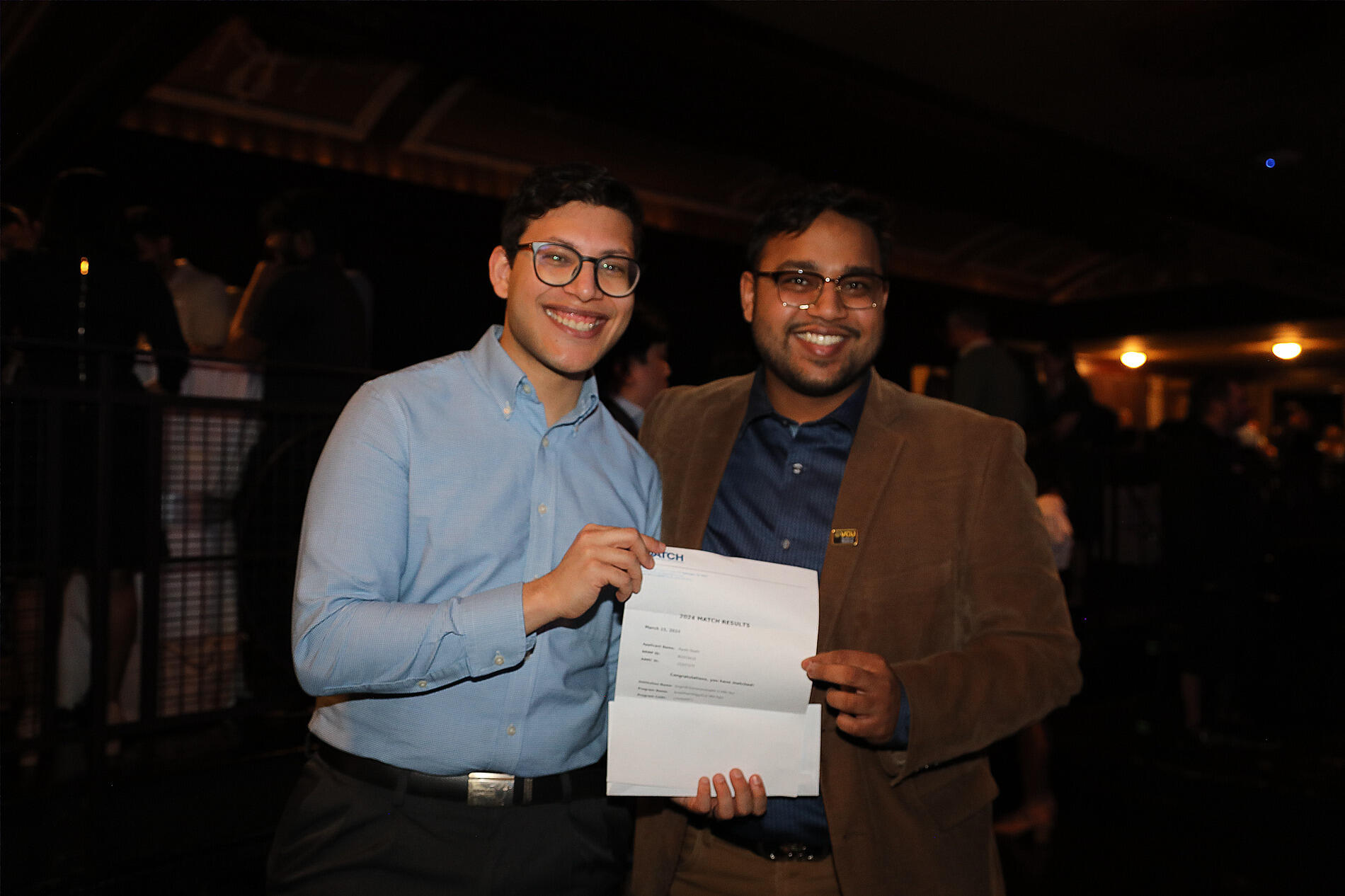A photo of two men holding a piece of paper and smiling. 