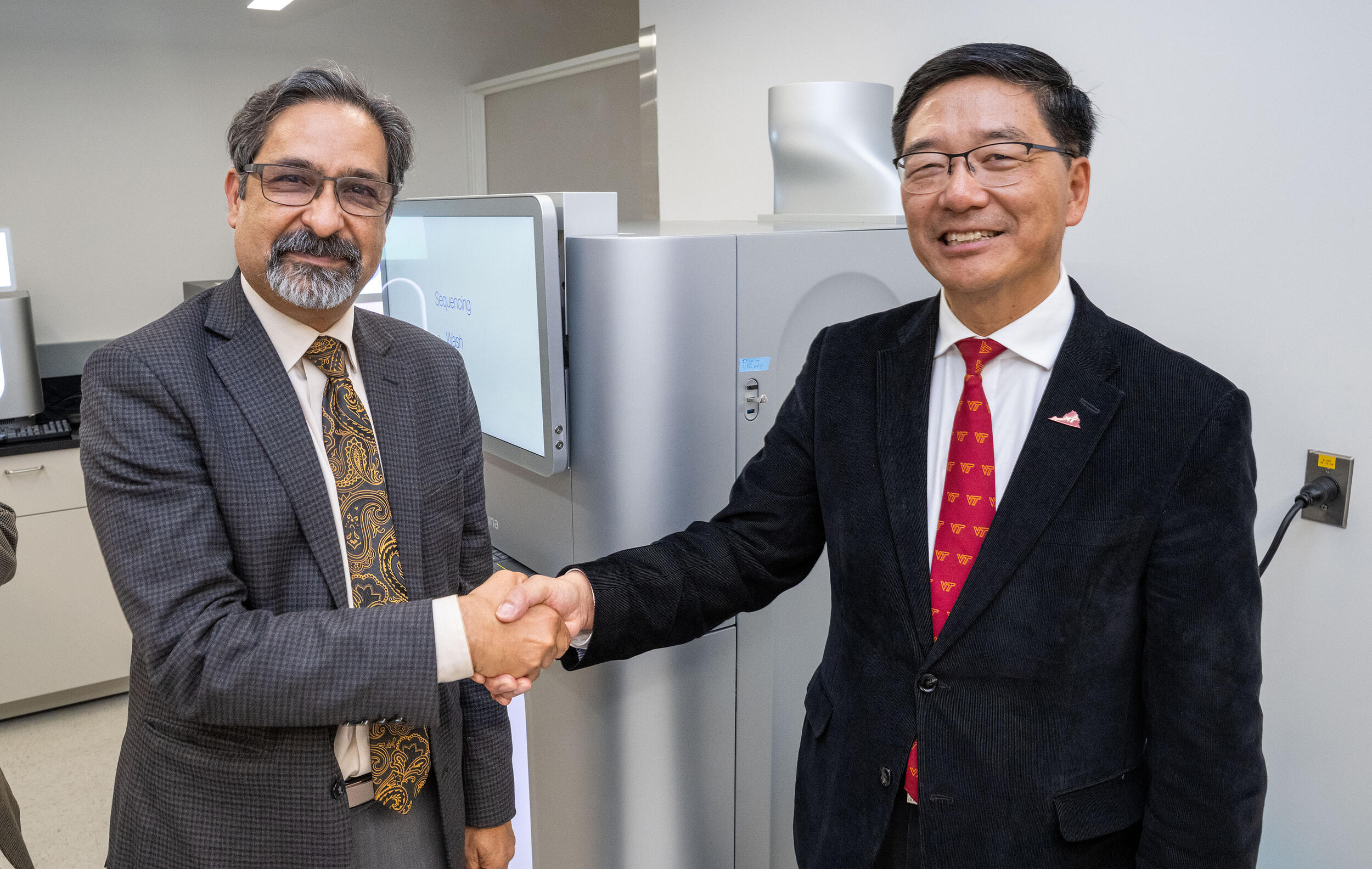 A photo of two men shaking hands and smiling. 