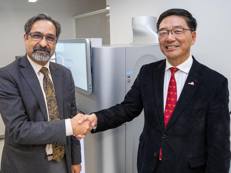 A photo of two men shaking hands and smiling. 