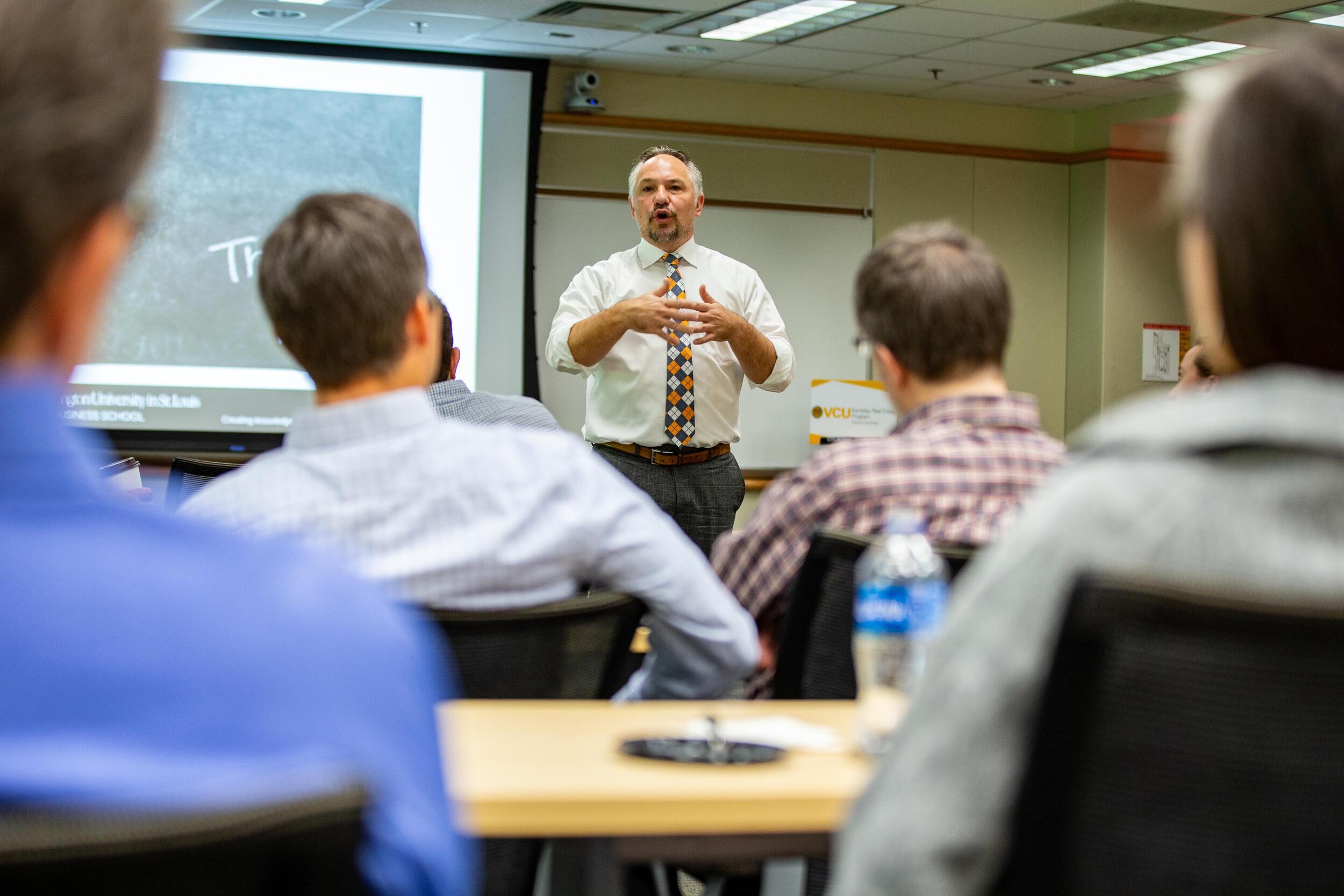A person giving a lecture to a group of students in a classroom.