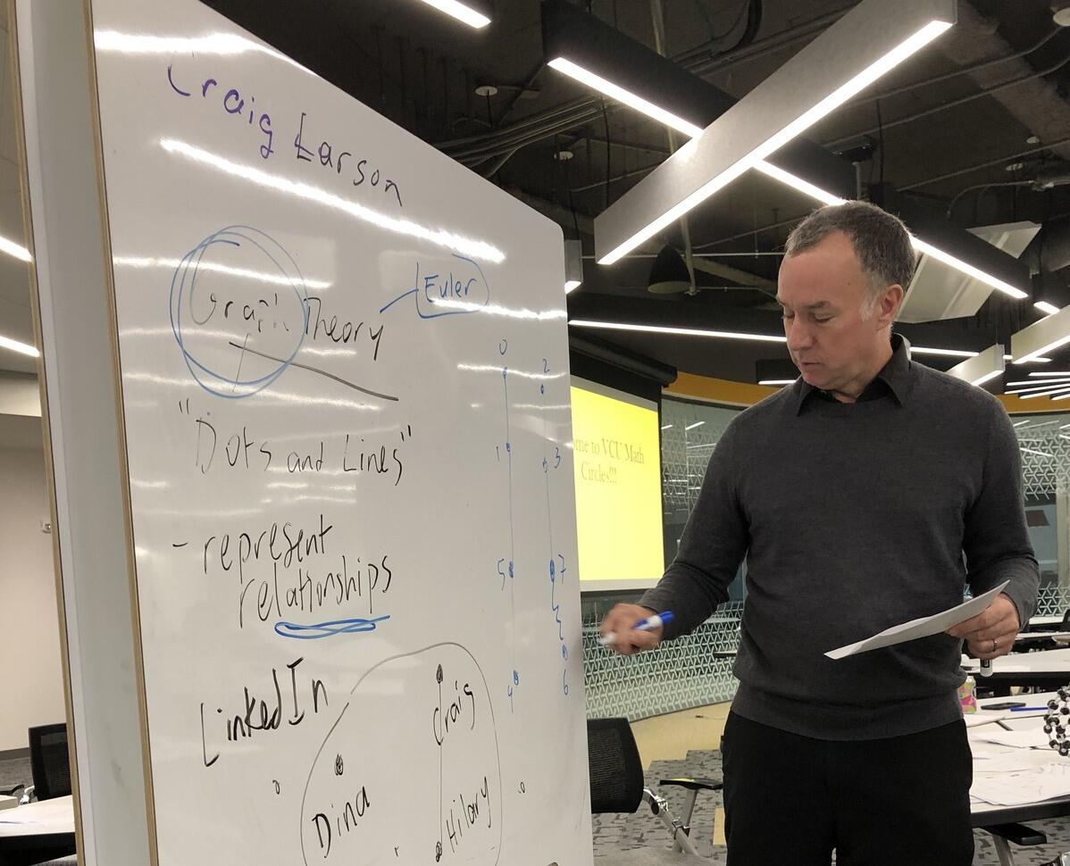A photo of a man standing next to a white board