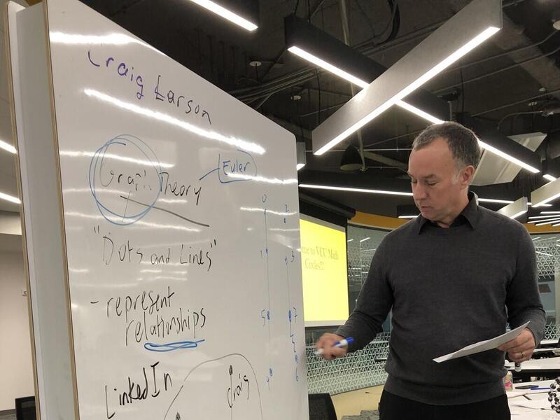 A photo of a man standing next to a white board