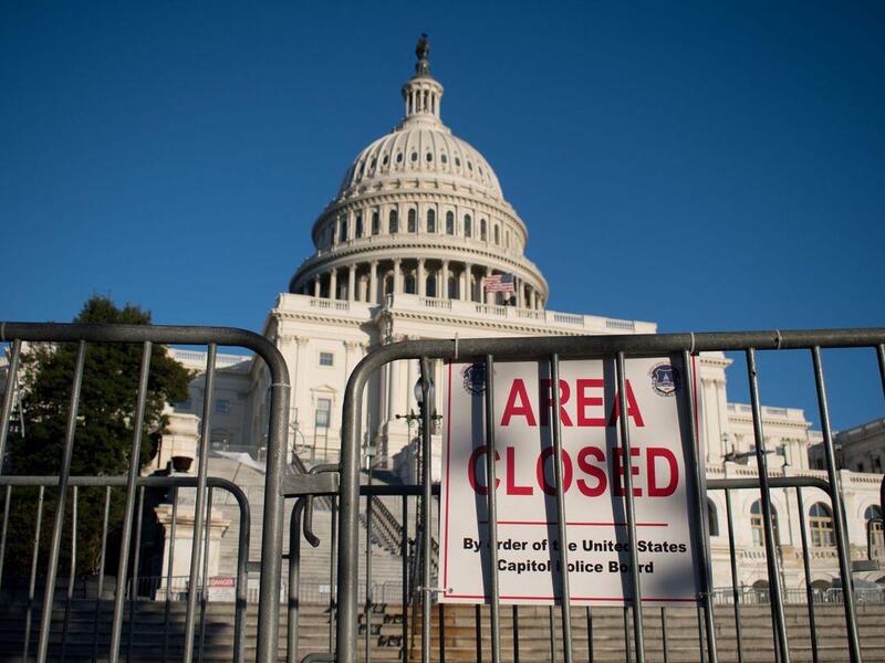 A photo of a gate in front of the U.S. Capitol with a sign that says \"A R E A C L O S E D\" in red letters. 