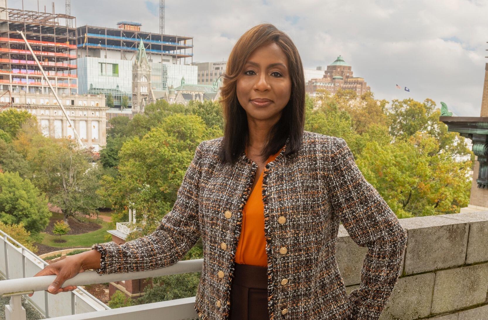 A woman leaning on a railing in front of trees and building construction. 