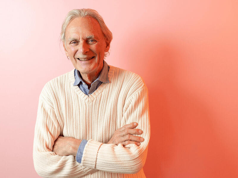 A photo of a man from the hips up. He is standing with his arms crossed against his chest. 
