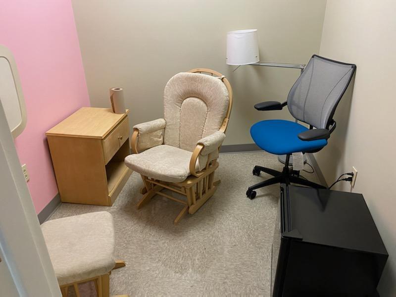 A room with two chairs, a lamp, a mini fridge, and a small side table 