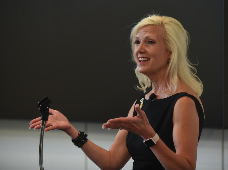A woman speaking with her hands out stretched in front of her. 