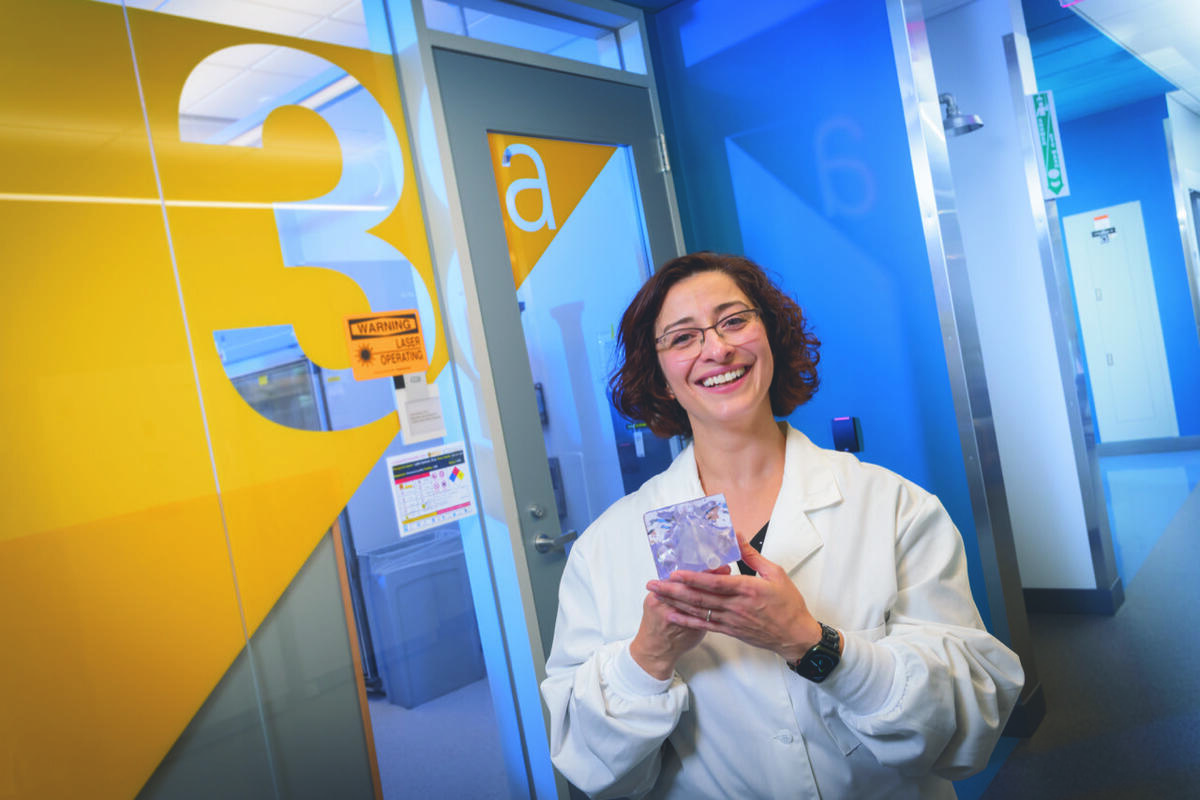 A photo of a woman wearing a white lab coat standing in a hallway 