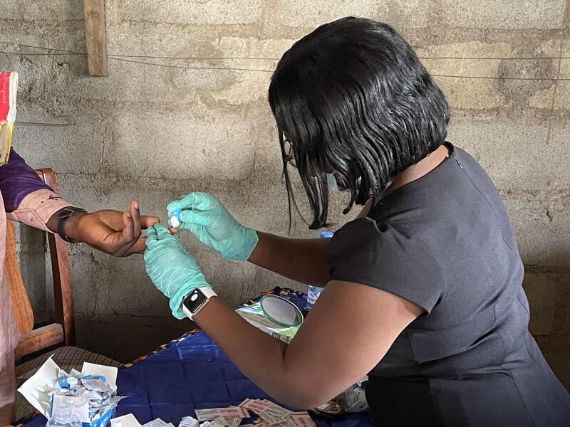 Pharmacy student Blessing Tomlah, right, gives free glucose tests to residents of her former hometown of Limbe, a rural agricultural community in Cameroon, during summer 2021.