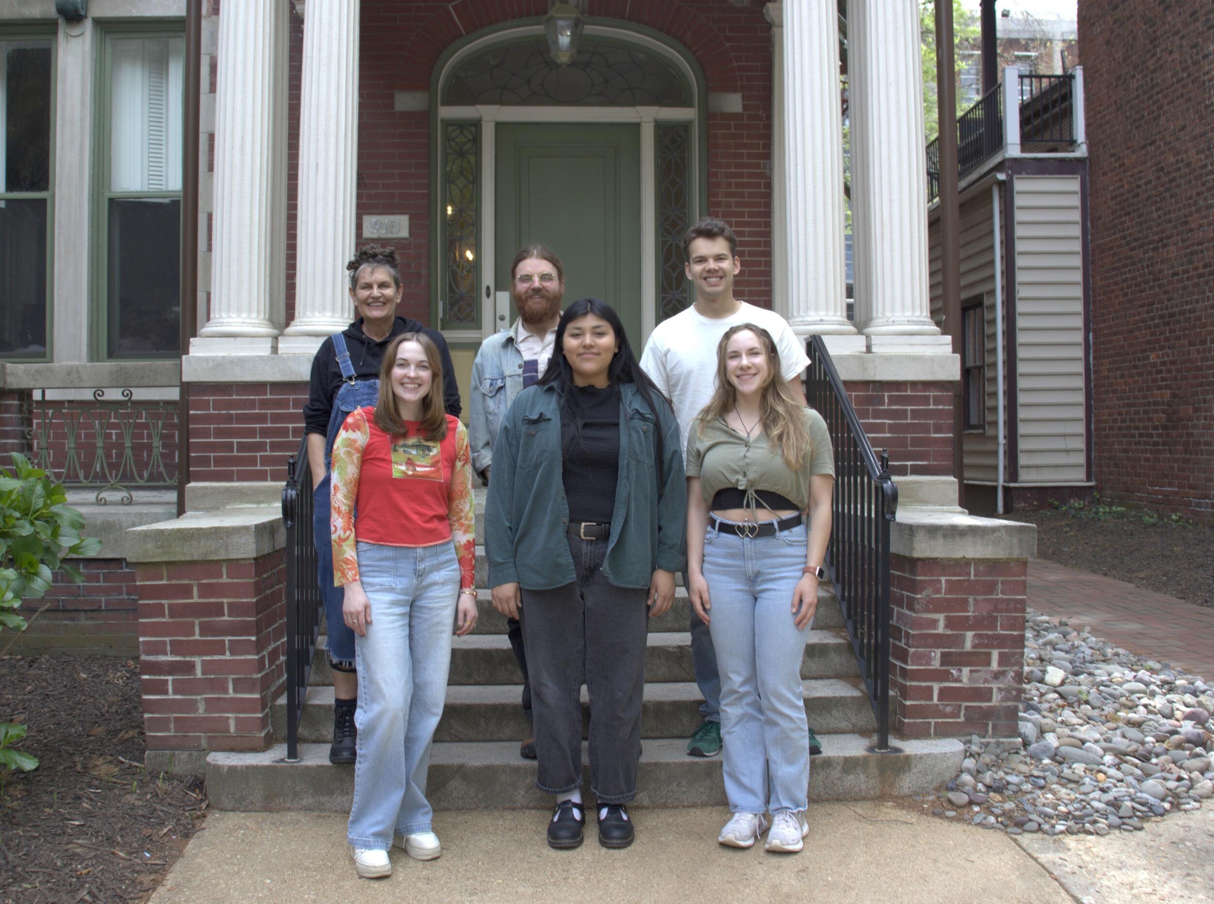 A photo of six people standing in front of the entrance to a building. 