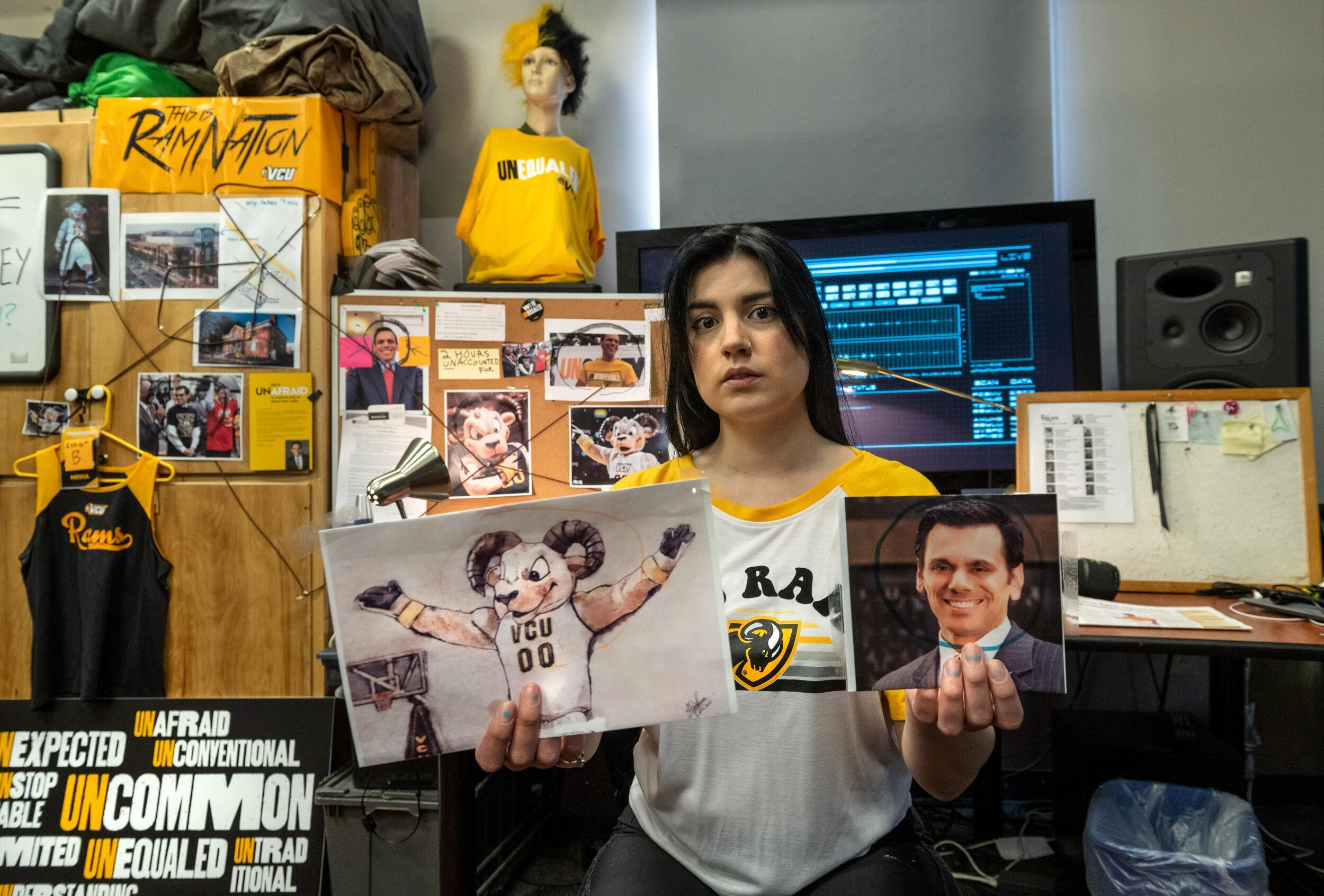 A woman holding a photo of a person in a ram costume and a portrait of a man. Behind her is a board with photos and string linking the pictures together. 