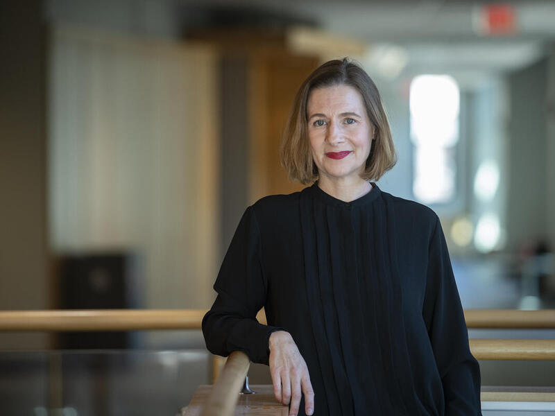 A photo of a woman wearing a black long sleeve shirt leaning against a railing. 