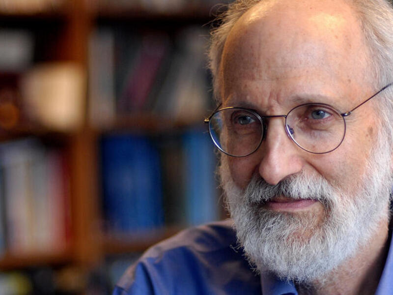 A photo of a man with white hair and a beard wearing glasses