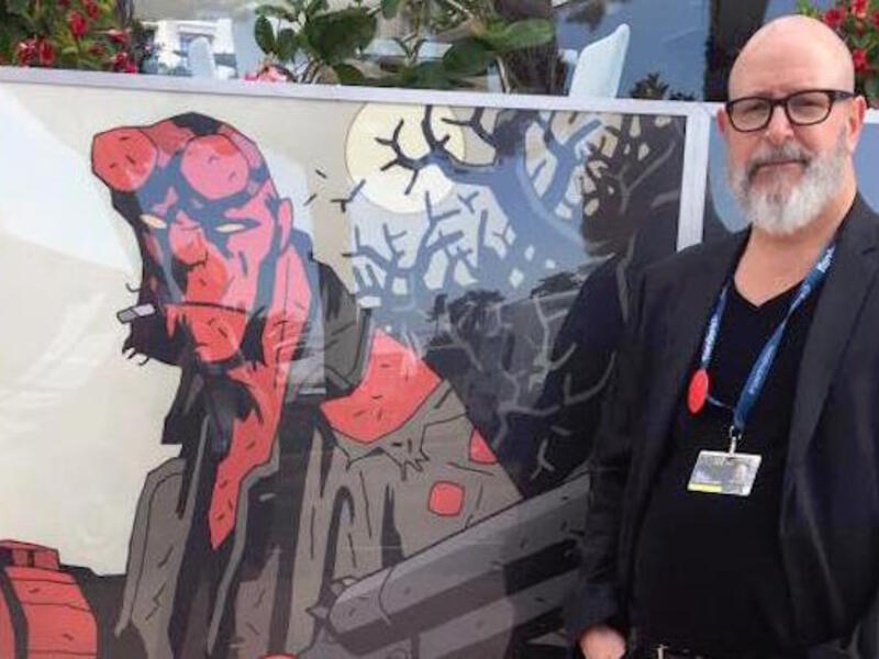 Hellboy creator Mike Mignola standing next to a picture of Hellboy comic character