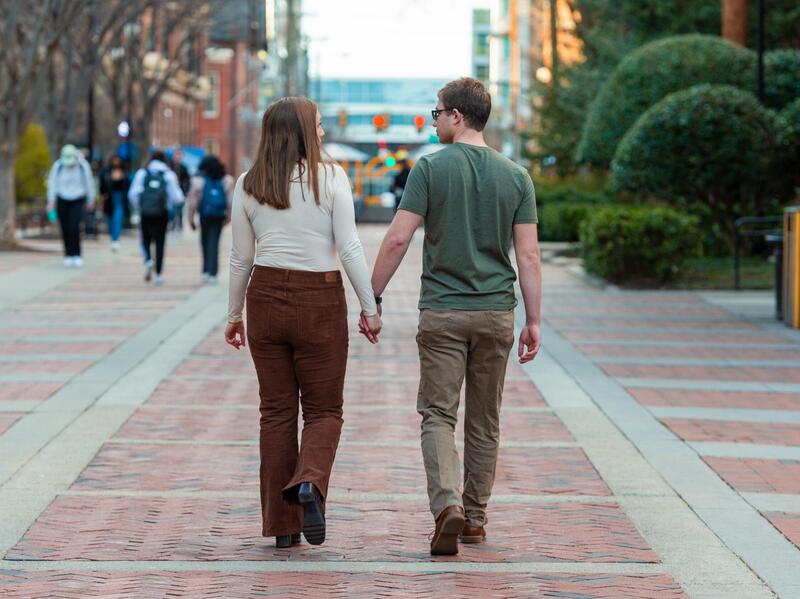 A couple holding hands while walking down VCU's Shafer Court.