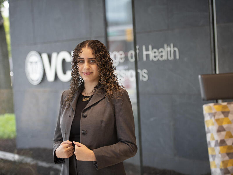 A woman wearing a coat standing in front of a building. 