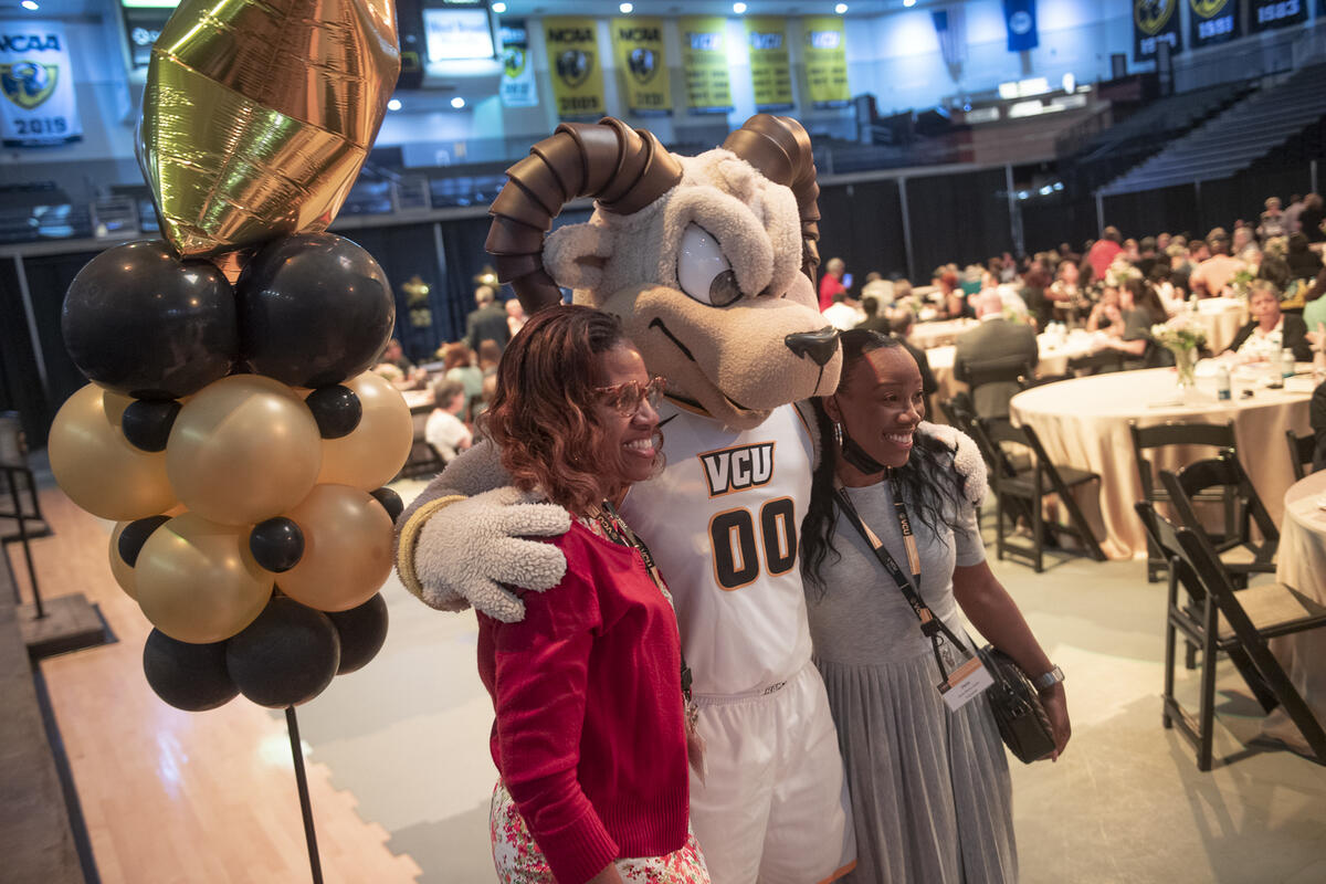 Rodney the Ram with his arms around two women