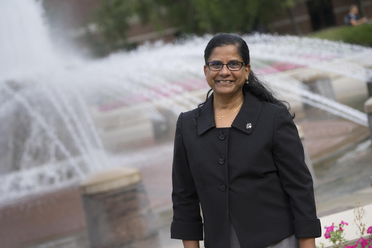 Mangala Subramaniam standing in front of a fountain 