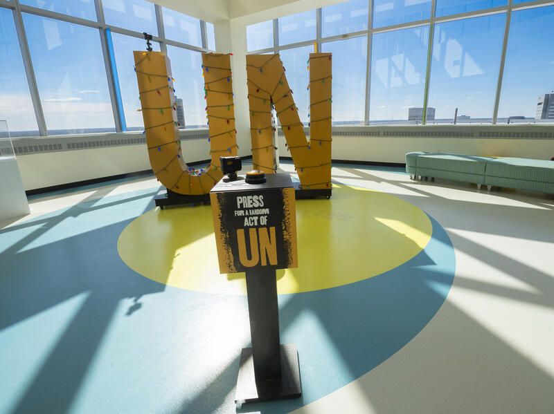 A photo of large yellow letters that say \"UN\" and have Christmas lights wrapped around them. 