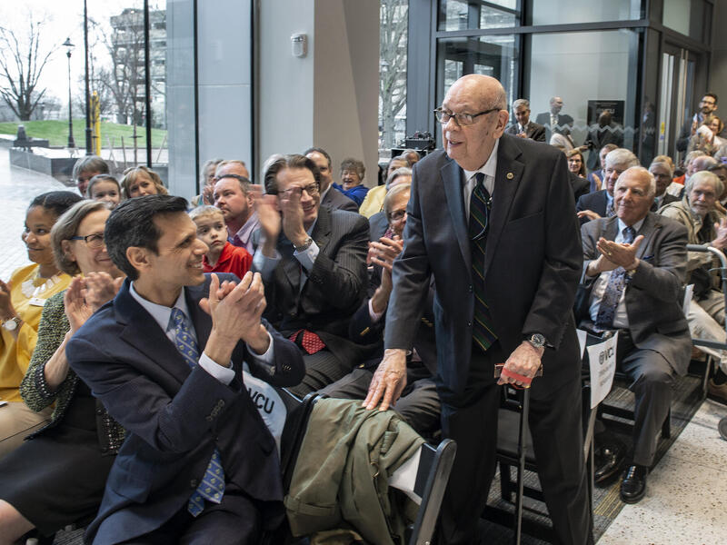 Thomas Barker, Ph.D., standing to be recognized by attendees of an event.