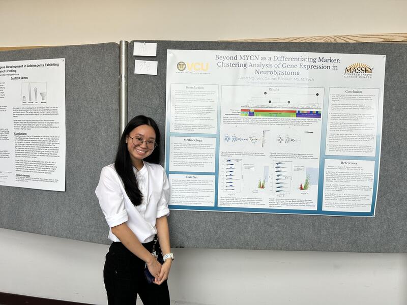 A photo of a woman from the legs up standing next to a poster with research on it. 