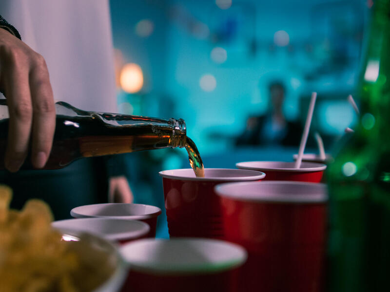 Liquid is poured from a bottle into a red plastic cup.