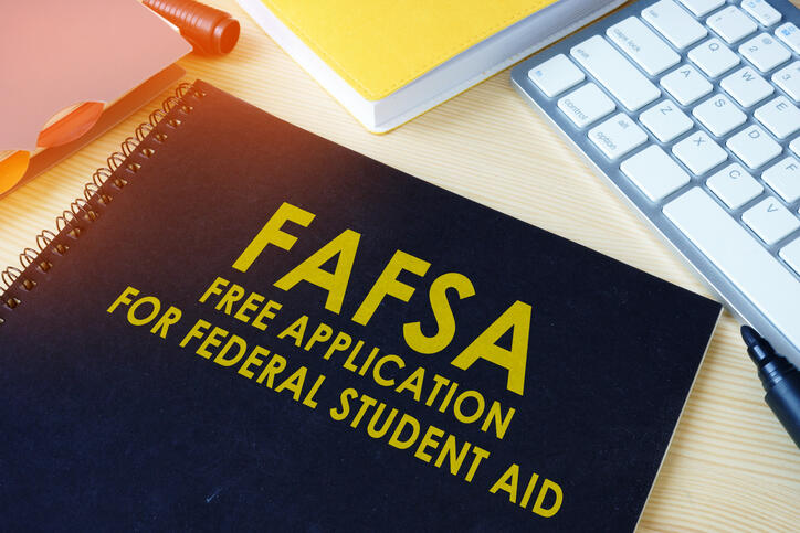 A photo of a black notebook that says \"FAFSA FREE APPLICATION FOR FEDERAL STUDENT AID\" in yellow letters. 