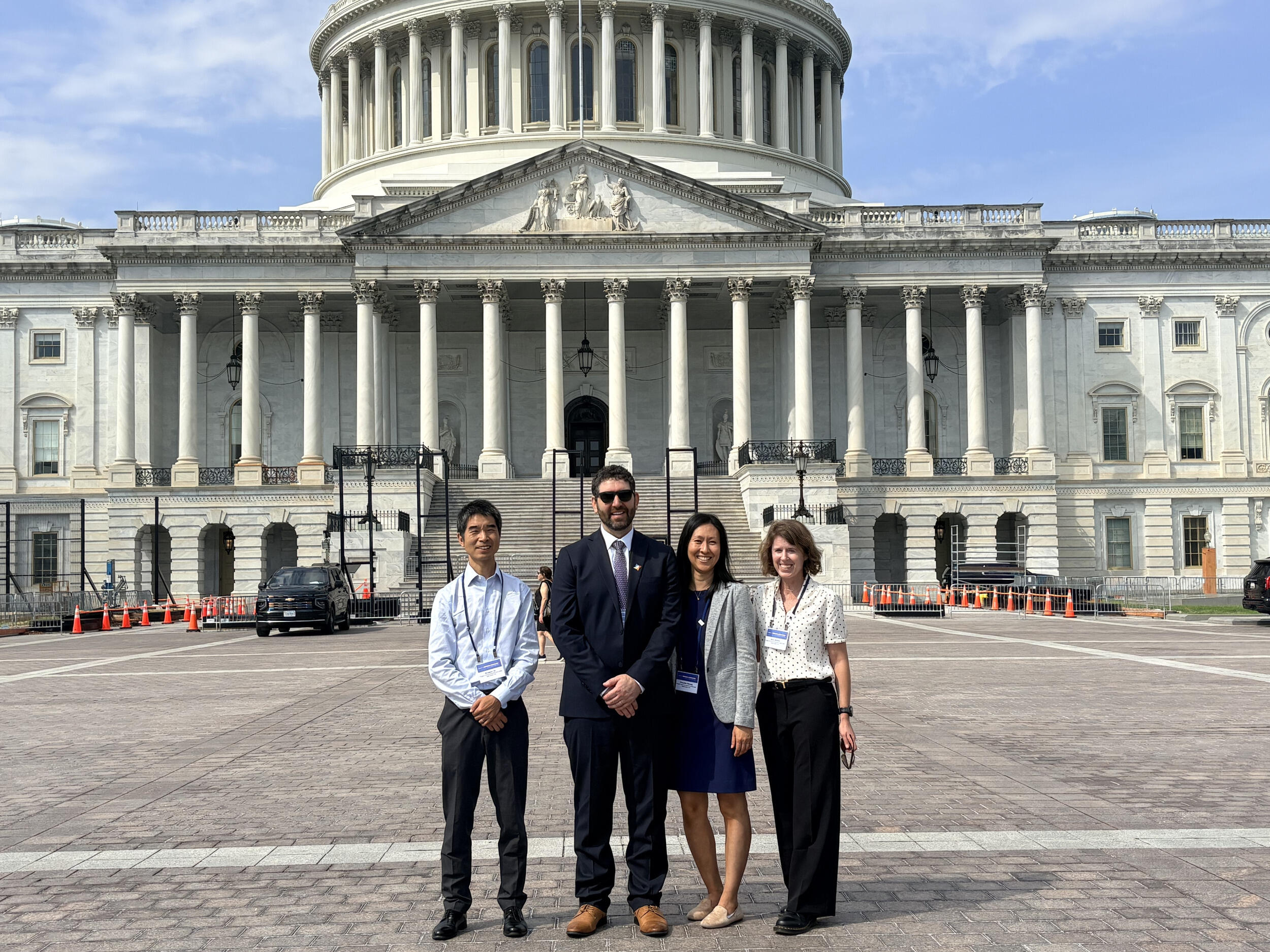 A photo of four people standing in front of the U.S. Capitol building. 