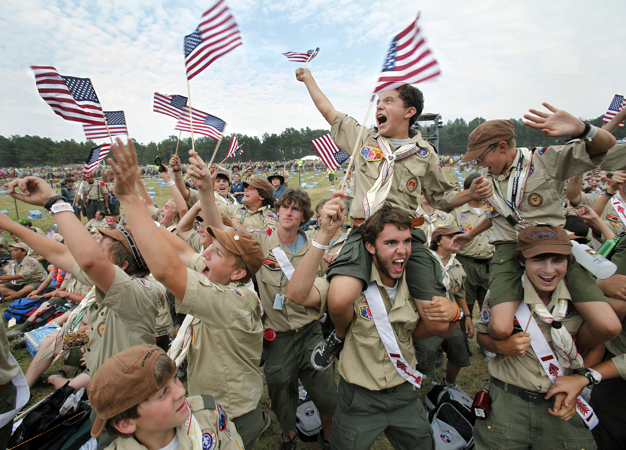 A group of boyscouts cheering and waving American flags