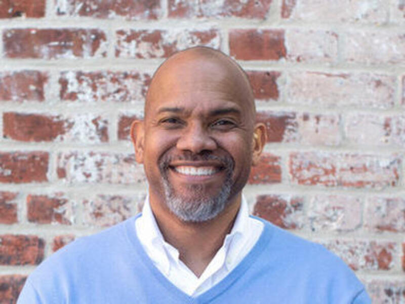 Vann Graves, Ph.D., smiling and standing in front of a brick wall
