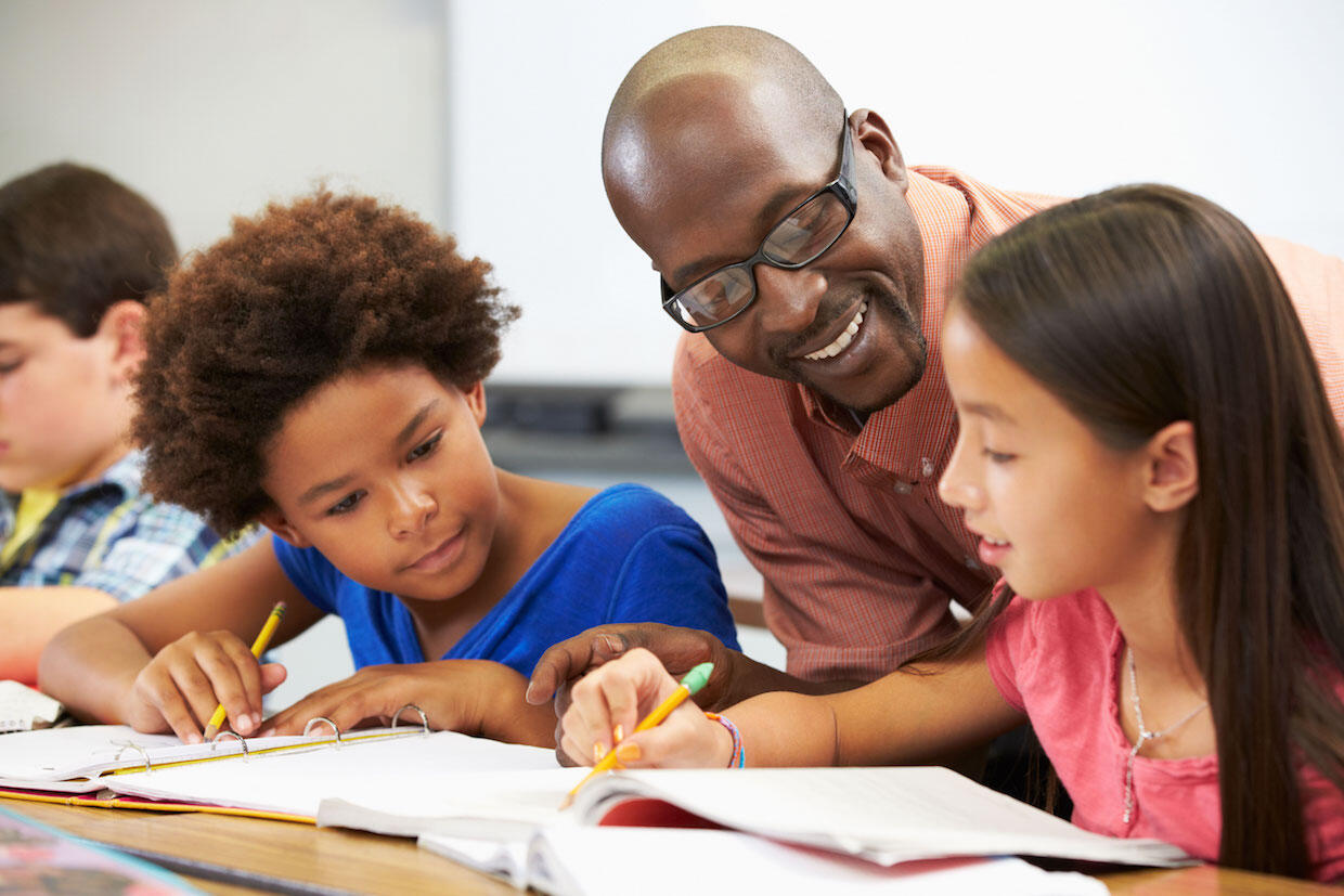 Young black male teacher helping his students with their classwork.
