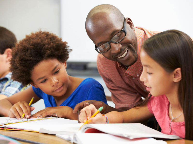 Young black male teacher helping his students with their classwork.