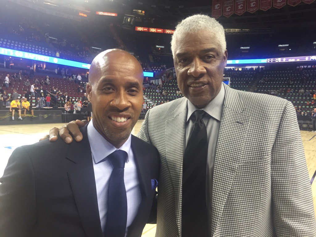Two men in suits on a basketball court.