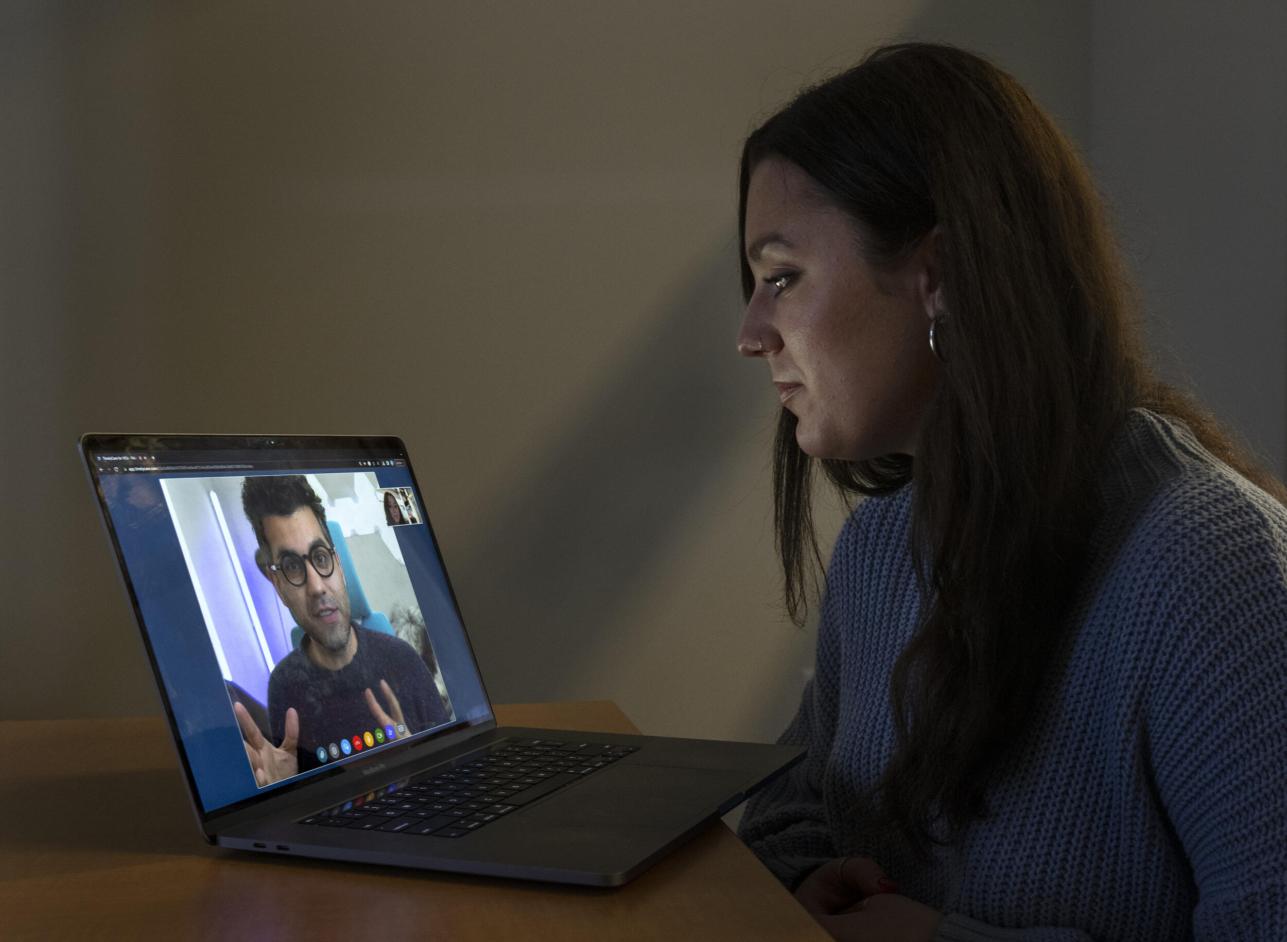 A student looks at a laptop screen, where a mental health provider is speaking.