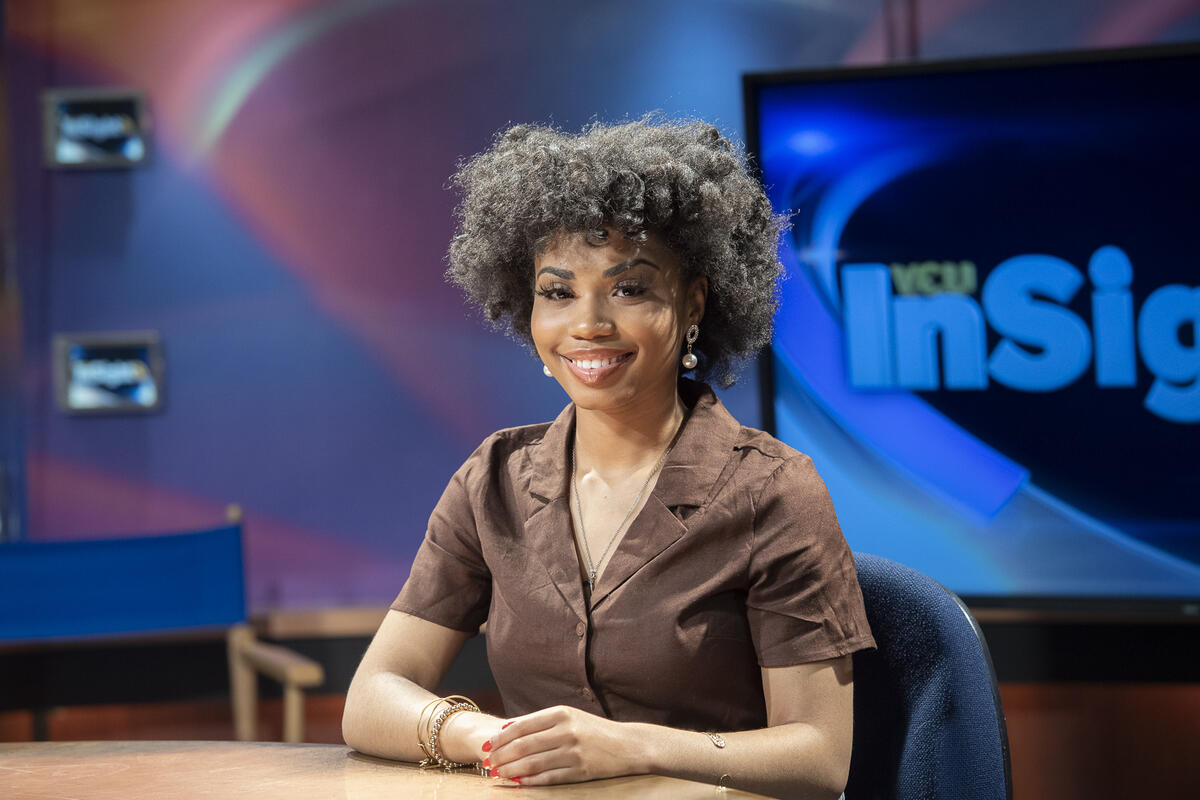 Gabriel Thomas sitting at a table with her hands resting on it.